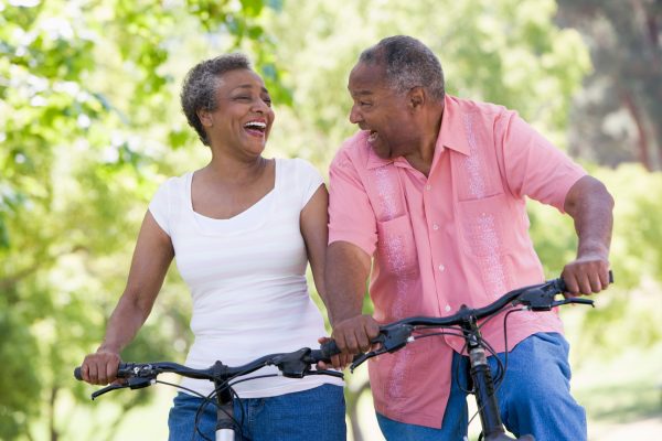 Elderly couple biking and laughing together