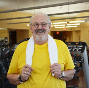 Senior man smiles while standing in a gym