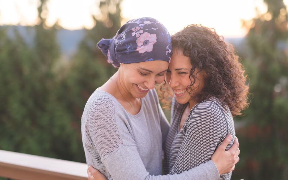Young breast cancer patient hugs her sister tightly