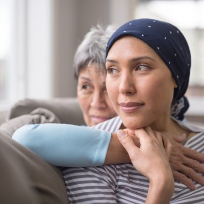 cancer patient and mother embrace on a couch