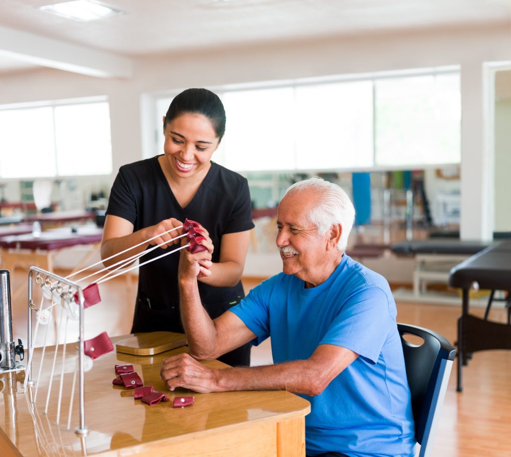 Happy senior man exercising hand with physical therapy device