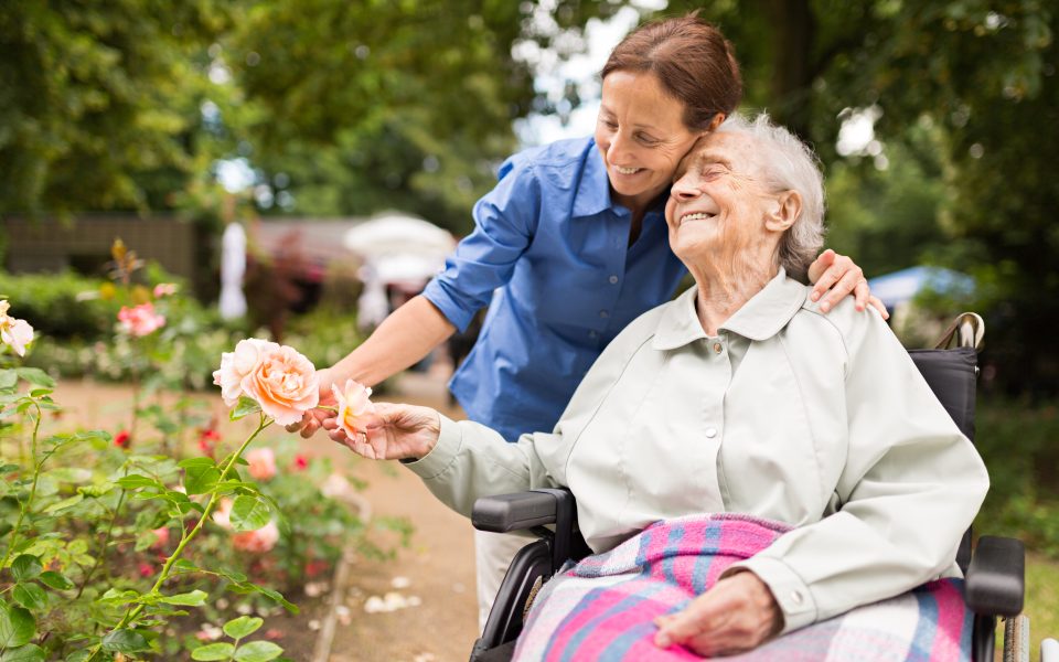Senior woman sitting on a wheelchair with caregiver