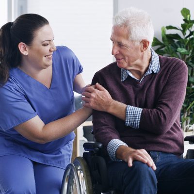 senior man in a wheelchair being cared for a nurse