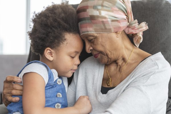 Senior woman with cancer lovingly holds granddaughter