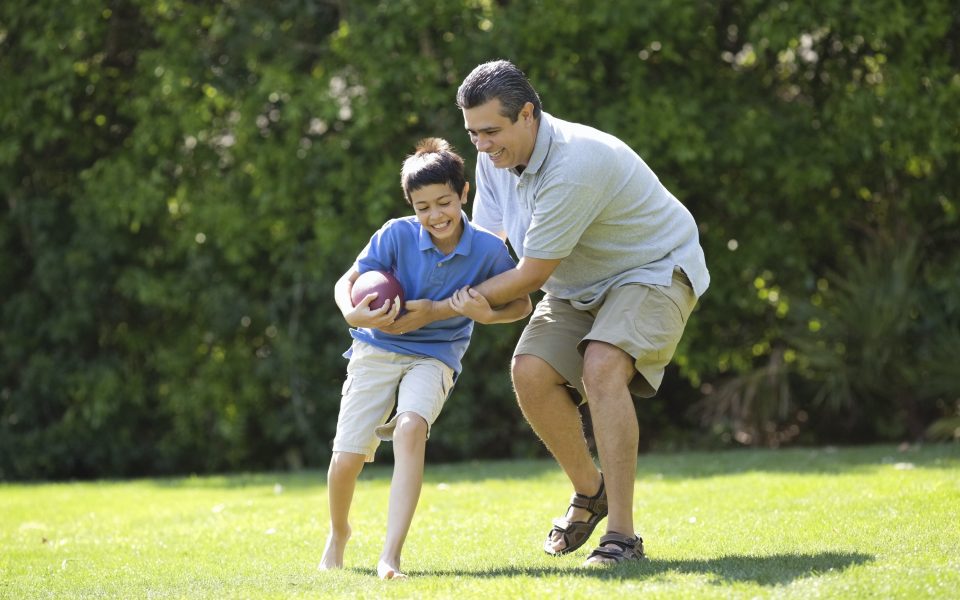 Father Playing American Football With Son