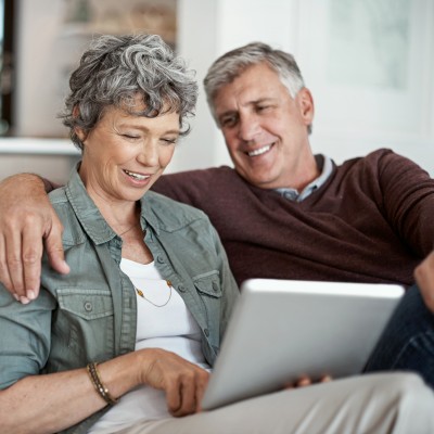 mature couple using a digital tablet while relaxing on their sofa