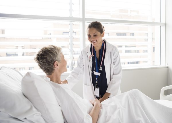 Female healthcare provider talking with female patient in a hospital bed