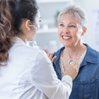 Female physician listens to senior patient's heart