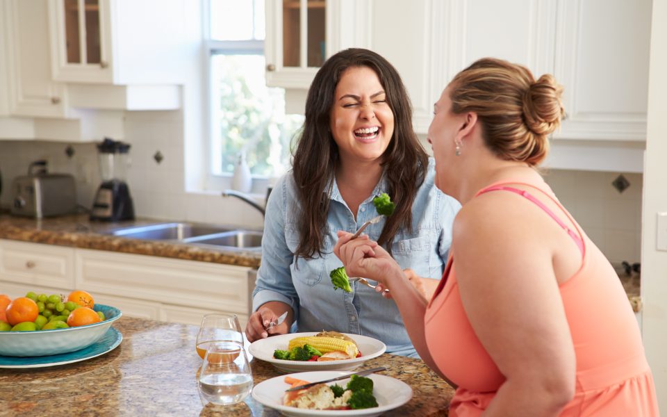 Two Women eating Healthy Meal In Kitchen