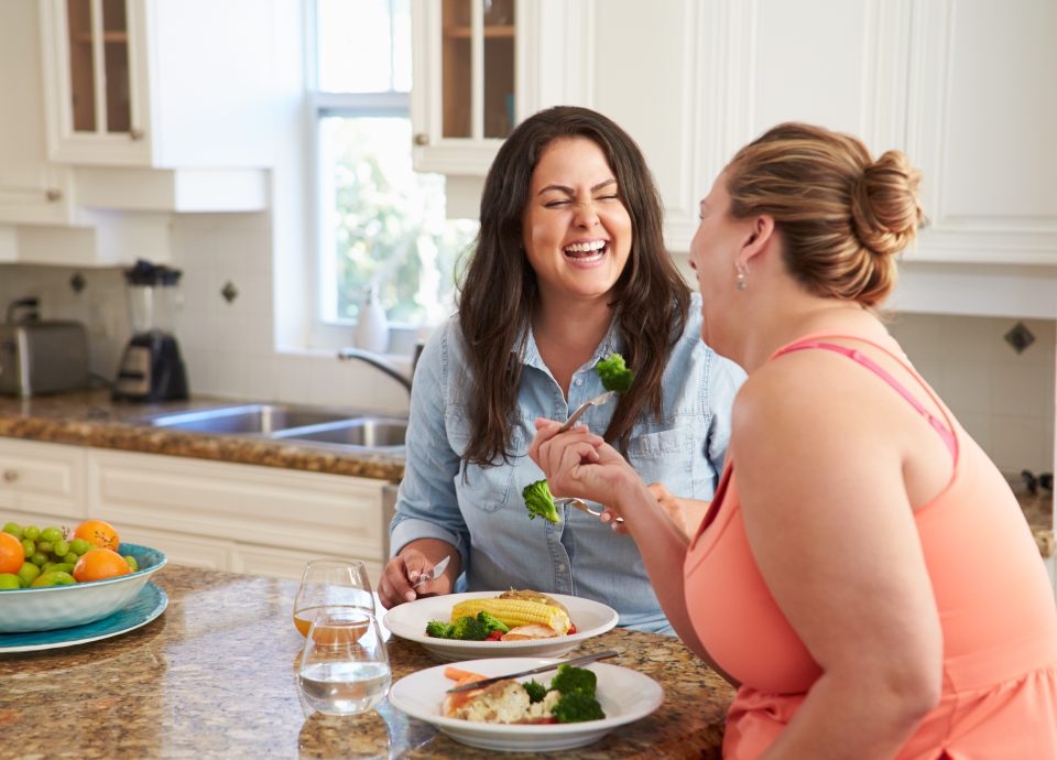 Two Women eating Healthy Meal In Kitchen