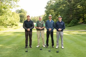 Four men posing on the golfing greens at Westchester Golf Course with their golf clubs