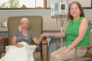 Paula Tipple holds hands with FMC volunteer during cancer treatment
