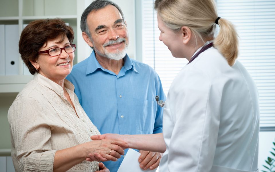 Husband and wife greeting female physician