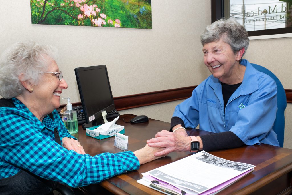 Volunteer smiling at female cancer patient at a desk