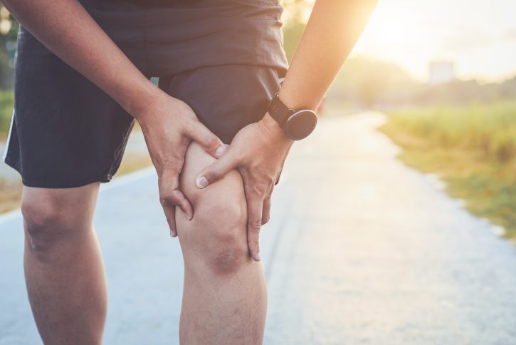 man holding knee in pain, runner's knee