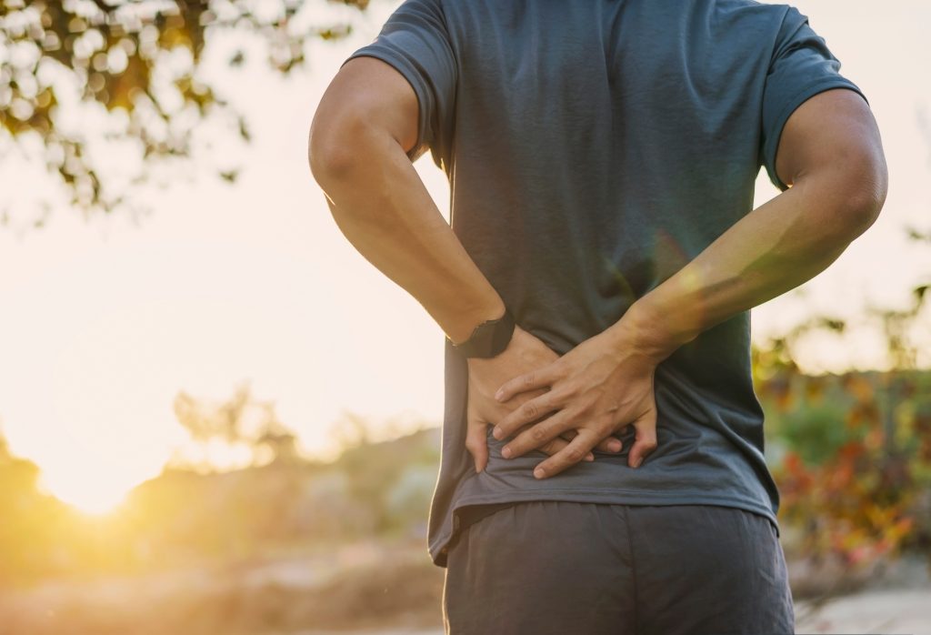 man grabbing back while outside working out