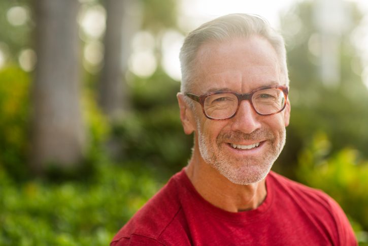 Mature man with glasses smiling outdoors